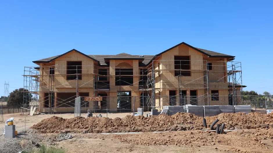 A large two-story suburban house under construction on a clear day.